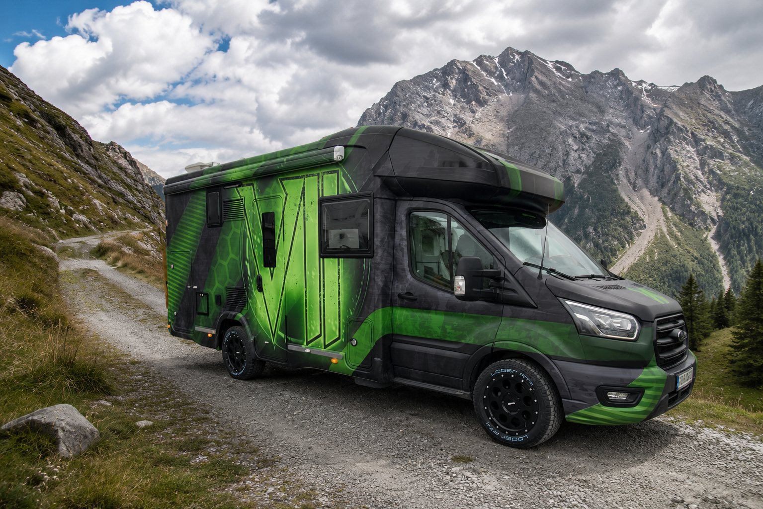 Grün schwarz gestaltetes Reisemobil in den Bergen